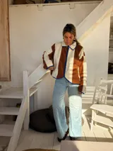 Campera de corderito con diseño de bloques de color, confeccionada en tejido sintético de textura suave. Presenta cierre frontal, cuello alto y ribetes en contraste en los bordes.