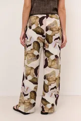 Pantalón largo beige de corte holgado con estampado floral en tonos marrones y violetas, y cintura con cordón ajustable.