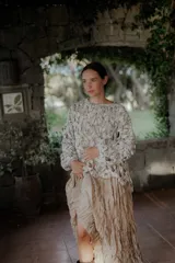 Buzo de tejido de punto calado con diseño de red, cuello redondo y mangas largas abullonadas. Presenta una textura jaspeada en tonos gris y blanco.