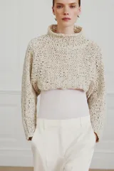 Jersey cropped de punto con textura de cinta entrelazada, cuello subido y manga larga.