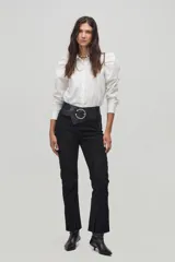 Pantalón recto color negro de cuero con aberturas en los tobillos y cierre lateral.