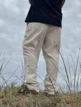 Pantalón de lino beige y crudo a rayas, de corte ancho y relajado.