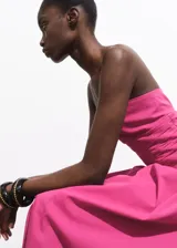 Vestido midi color fucsia, sin mangas, con escote palabra de honor, detalles fruncidos en los laterales del torso y falda evasé.
