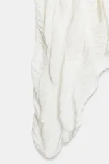 Top de cuello redondo color celeste con textura fruncida, mangas tipo capa y bajo asimétrico.