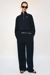 Pantalón tipo jogger de tiro medio con cintura elástica ajustable mediante cordones. Presenta un diseño de pierna recta, bolsillos laterales ocultos en las costuras y un detalle metálico con el logo ZA en la parte superior.