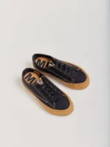 Championes de lona negra con plataforma y puntera de goma marrón, cordones negros y costuras en contraste.