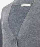 Cardigan de punto color beige con escote en V, cierre frontal con botones grandes y mangas largas con puños acanalados. Presenta un corte recto y estructurado.