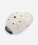 Gorra de sarga color blanco crudo, con visera curva, costuras contrastantes y bordado frontal con el texto "Tokyo" en color azul marino.