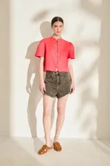 Blusa de lino color amarillo, con cuello mao, cierre frontal con cremallera y mangas cortas abullonadas. Cuenta con un bolsillo aplicado en el frente.