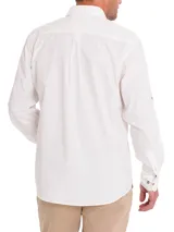 Camisa de manga larga color blanco, confeccionada en popelina de algodón orgánico. Presenta cuello camisero, cierre frontal con botones de madera, un bolsillo en el pecho y mangas ajustables con botones.