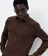 Camisa de corte slim, manga larga, con cuello camisero y cierre frontal de botones. Confeccionada en tejido plano de bambú, viscosa, poliéster y elastano.