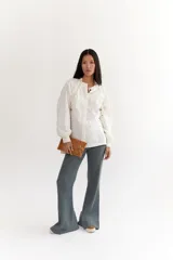 Sobre de cuero negro con solapa, cierre magnético y muñequera con tachas plateadas.