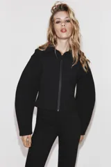 Chaqueta entallada de tejido efecto neopreno en color negro, con cuello solapa amplio, cierre frontal con cremallera y mangas largas abullonadas.