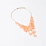Collar dorado con colgantes en forma de pétalos color durazno.