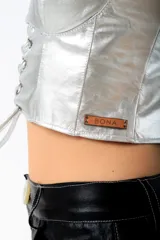 Corset plateado de cuero sintético con tirantes finos y ajuste frontal con cordones.