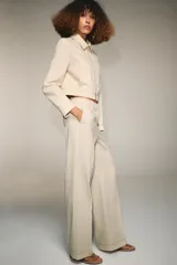 Pantalón de tiro alto con trabillas, bolsillos laterales y cierre frontal con cremallera y gancho metálico. Presenta un diseño de corte recto con costuras decorativas a contraste en la cintura y el ruedo.