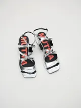 Sandalias de cuero con acabado de charol metalizado en color dorado, con tiras cruzadas en el empeine, taco cuadrado de 4,5 cm y correa ajustable en el tobillo.
