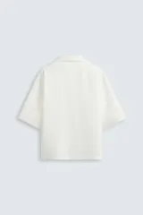 Camisa de corte relajado confeccionada en tejido mezcla de lyocell, con cuello solapa, manga corta y cierre frontal con botonadura oculta.