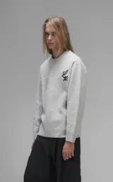 Sweater de cuello redondo color gris melange, con diseño de punto texturado y bordado en relieve con las letras 'Lx.' en el pecho. Presenta terminaciones en punto rib en cuello, puños y ruedo.