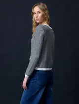 Cardigan de tejido tweed celeste y blanco, con escote redondo, cierre frontal con botones metálicos dorados y bolsillos simulados en el frente.