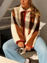 Campera de corderito con diseño de rayas verticales en colores marrón y crema, con cierre frontal y detalles de ribete en color rojo.