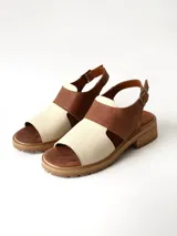 Sandalias de cuero combinadas en color marrón y crudo, con suela track y taco bajo. Tienen tira ajustable con hebilla en el talón.