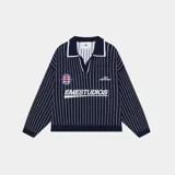Polo de punto de manga larga con diseño de rayas verticales blancas sobre fondo azul marino. Presenta cuello tipo polo con solapa, corte holgado y detalles bordados y tipo parche en el frente con el logo de la marca.