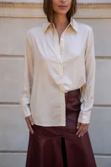 Camisa de manga larga color negro con apliques de strass plateados distribuidos en todo el diseño. Presenta cuello clásico, cierre frontal con botones y puños abotonados.