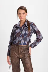 Camisa corta estilo corset de color blanco, con cuello clásico, cierre frontal de botones y detalles de cordones laterales ajustables. Presenta pinzas frontales y traseras para un ajuste entallado.