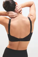 Top deportivo negro con diseño de escote redondo y detalle de costuras decorativas en el frente. Confeccionado en tejido técnico elástico, ofrece soporte y ajuste al cuerpo.