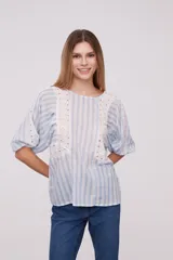 Blusa blanca con rayas verticales celestes, mangas abullonadas y detalles de calado en los hombros y el frente.