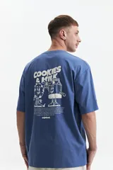 Remera azul de manga corta con corte oversize y cuello redondo. Estampado en la espalda con la frase "Cookies & Milk" y dibujos de una galleta y un cartón de leche.