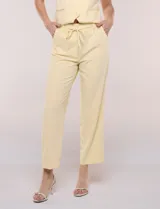Pantalón sastrero color amarillo, de corte recto y largo al tobillo. Cuenta con cintura con presillas, fino cordón textil para anudar, bolsillos laterales y pinzas de entalle.