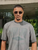 Remera de jersey con efecto teñido, color marrón, de corte holgado y cuello redondo. Presenta un estampado frontal con texto en tonos más oscuros.