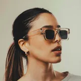 Lentes de sol unisex con armazón rectangular de acetato transparente en tono rosado y cristales oscuros.