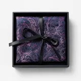 Pañuelo de bolsillo de seda con estampado floral y botánico en tonos violeta y azul oscuro, presentado en una caja de regalo negra con cinta.