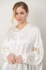 Camisa de satén tramada color blanco, con calce holgado y cómodo, cuello camisero, mangas largas y cierre frontal con botones.