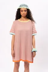 Vestido corto tejido de punto color salmón, con cuello redondo y mangas cortas. Presenta ribetes en color amarillo en el cuello, celeste en las mangas y naranja en el ruedo.
