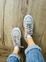 Zapatillas bajas de lona color blanco, con cordones marrones, puntera de goma y base blanca.