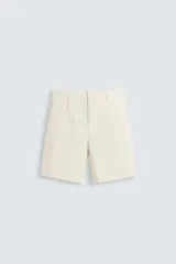 Bermuda de hombre color beige claro, corte regular fit, con pliegues frontales, bolsillos delanteros y bolsillos traseros de doble vivo con botón.