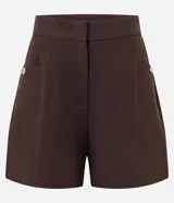 Short sastre de cintura alta, color blanco, con bolsillos laterales y detalles de tachuelas metalizadas.