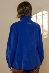 Camisa de pana azul marino con cuello alto tipo mao con volados, cierre frontal de botones y mangas largas con puños abotonados.
