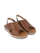 Sandalia de cuero color camel con tiras cruzadas en el empeine y tira trasera con elástico. Cuenta con una suela plana de goma con detalle de franja blanca y base dentada.