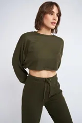 Buzo corto de tejido rib en color verde militar, con mangas largas y cuello redondo. Presenta un diseño holgado y cropped.