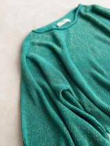 Buzo de tejido de punto con acabado brillante, confeccionado con hilado italiano. Presenta cuello redondo, mangas largas acampanadas y un corte holgado.