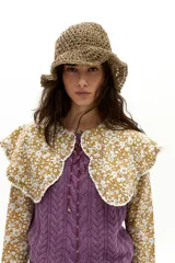 Camisa de popelina de algodón color mostaza con estampado floral blanco. Presenta un cuello amplio con terminación ondulada y encaje de algodón crudo, mangas largas y botones de nácar en el frente.