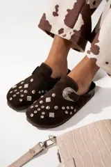 Suecos de cuero gamuzado color marrón chocolate, con apliques de tachas plateadas y hebilla decorativa metálica.