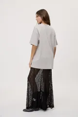 Remera oversized de manga corta y cuello redondo, de color negro con efecto acid wash y aplicación de strass en la parte superior.