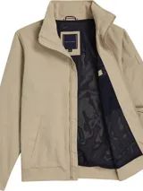 Campera Tommy Hilfiger color beige con cuello alto y cierre de cremallera. Tiene dos bolsillos laterales, detalles distintivos de la marca y logo engomado bordado en la manga.