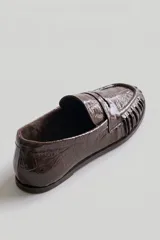 Mocasín de cuero marrón con textura croco y acabado brillante, de diseño clásico con detalle de antifaz en el empeine y costuras pespunteadas alrededor de la puntera.